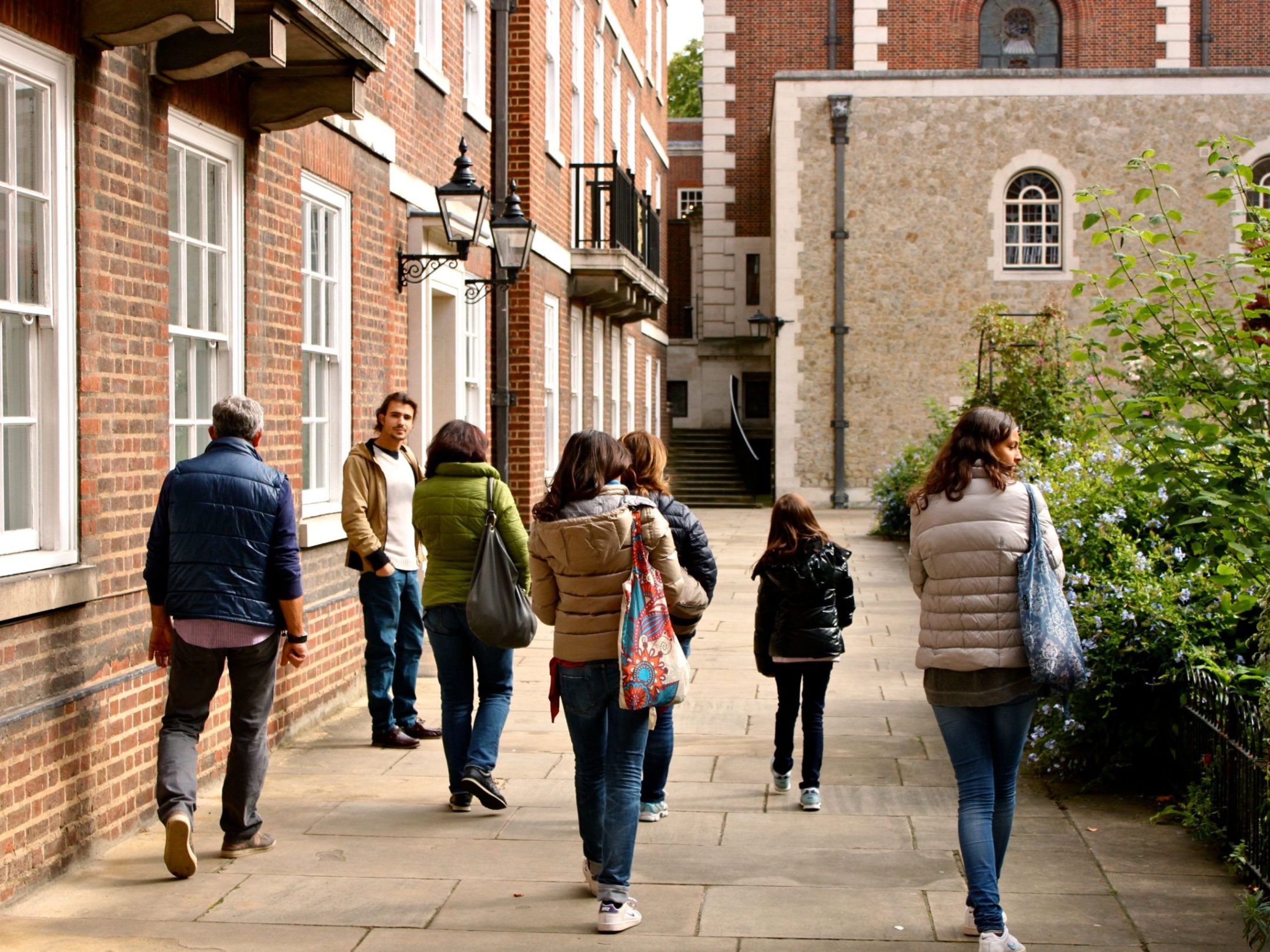 a group of people walking down a street next to a brick building