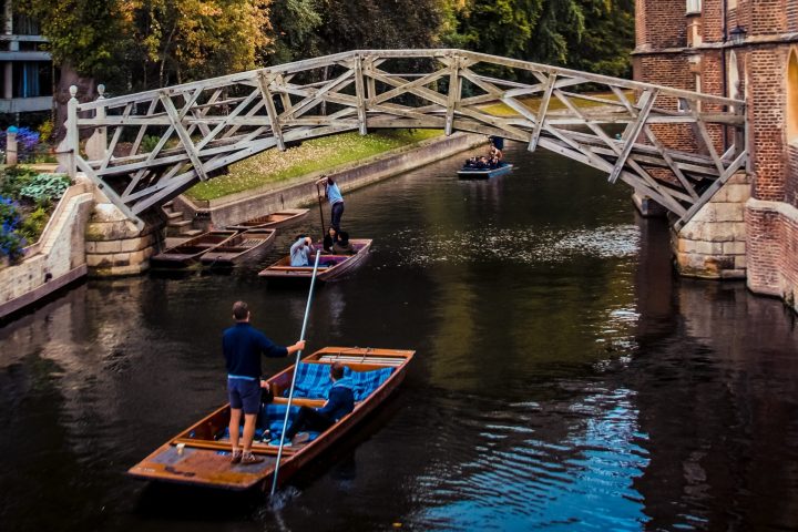 a man riding on the back of a boat next to a river