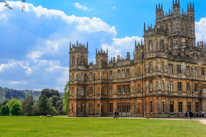 a castle on top of a grass covered field with Highclere Castle in the background